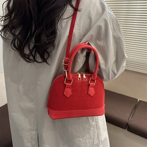 Red leopard texture shell bag with gold hardware worn as a crossbody by a model