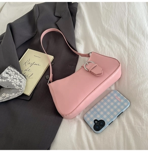 Detail of a pink French-style baguette bag with silver buckle on a soft fabric