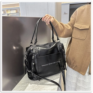 Detail of a black shiny faux leather biker tote bag with silver zippers and handles