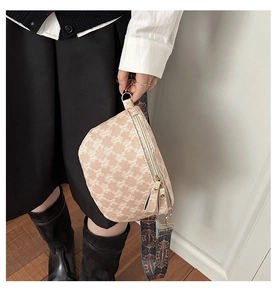 Detail of pink monogram crossbody bag with golden zipper and woven decorative strap
