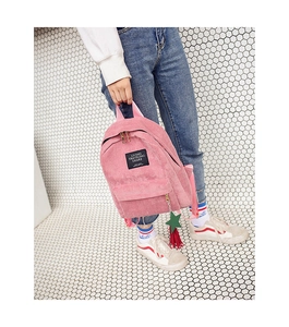 Close-up of pink corduroy backpack with star pendant and woven text label on front pocket