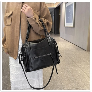 Detail of black glossy faux leather handbag with motorcycle style tassels and rivets