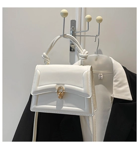 Detail of white faux leather handbag with braided knot handle and gold twist lock
