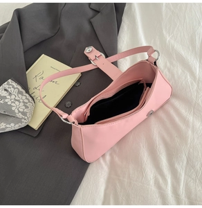 Detail view of pink baguette bag with silver buckles on white sheets and grey blazer