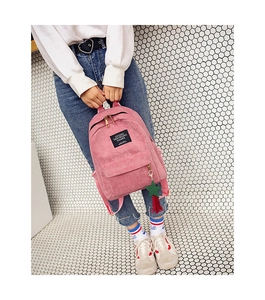 Detailed shot of pink corduroy backpack with green star charm and tassel accessory