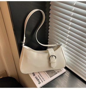 Close-up of cream white baguette bag with silver buckle on a minimalist windowsill