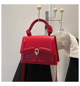 Detail of red leather crossbody bag with golden buckle and creative knot handle