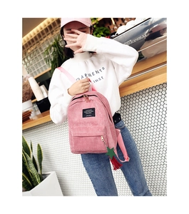 Detailed texture of pink corduroy backpack with woven label and star charm accessory