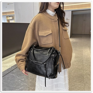 Detail of black glossy faux leather tote bag with stylish zipper accents and handle
