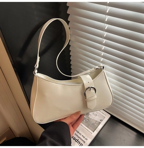 Detail of creamy white baguette bag with a stylish silver metal buckle strap