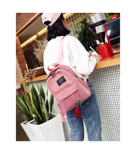 Detailed close-up of pink corduroy backpack featuring colorful star tassels and velvet texture
