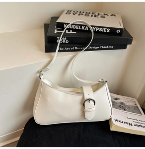 Close-up of a white baguette shoulder bag with a large silver buckle on a minimalist set