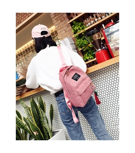Detailed view of pink corduroy backpack with letter patch and red tassel accessory