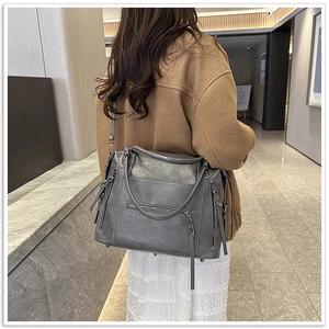 Detail of grey soft leather motorcycle bag featuring tassel zippers and adjustable strap