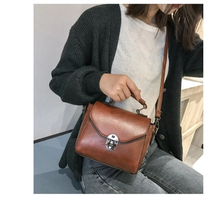 Dettaglio borsa a tracolla vintage in pelle marrone con chiusura a scatto e manico