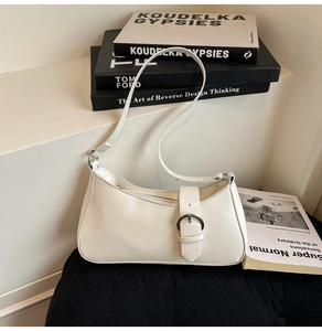 Detailed view of white baguette bag featuring smooth PU leather and silver buckle strap