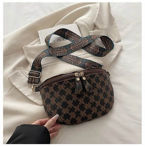 Close-up of semi-circular crossbody bag with M-pattern and ethnic woven strap details