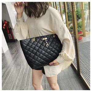 Detail of black quilted tote bag with golden deer charm and chain shoulder strap