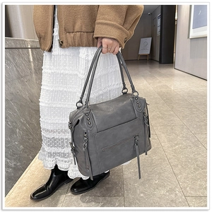 Detail of dark grey leather tote bag with tassels and rivets in a lifestyle setting