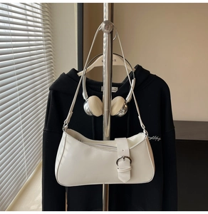 Detail of white baguette bag featuring a wide strap and polished silver round buckle