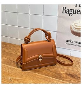 Detailed macro of caramel leather bag with golden ring twist lock and handle knot