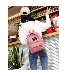 Pink corduroy mini backpack with colorful star tassel charm in a cozy cafe setting