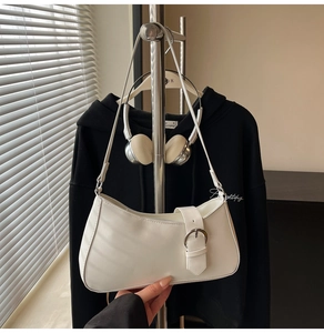 Detail of white PU leather baguette bag featuring silver buckle and sleek crescent design