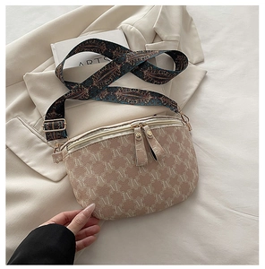 Close-up of beige monogram shoulder bag with colorful woven strap on a white blazer