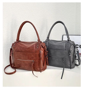Close-up of dual tote bags in brown and grey featuring multiple zipper pockets and textures