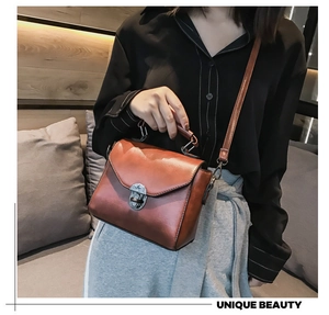 Dettaglio di una borsa a tracolla vintage in pelle marrone con chiusura girevole argento