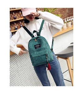 Detail of dark green corduroy backpack with zipper pocket and red tassel pendant