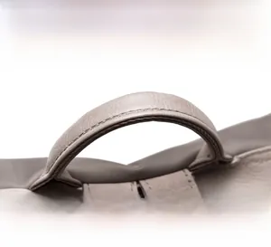 Close-up of the reinforced gray leather handle with fine stitching on an oxford fabric bag