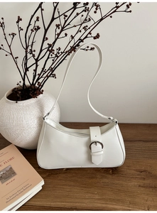 Minimalist white baguette bag on wooden surface with floral decor and soft studio lighting