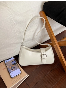 Close-up of minimalist white baguette bag with silver ring buckle in home setting
