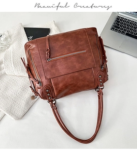 Detailed view of brown vintage leather tote bag with metal rivets and long tassels