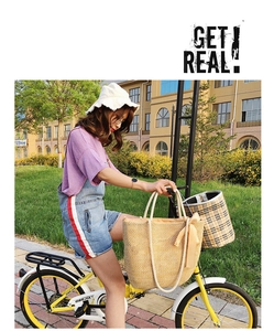 Detail of yellow woven straw tote bag with satin bow decoration on a vintage bicycle