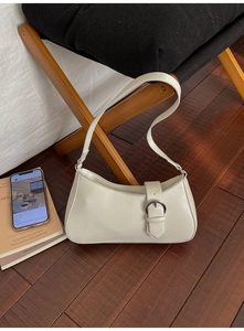 Detail of white faux leather underarm bag with silver buckle on a wooden floor