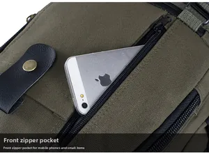 Detail of front zipper pocket on army green canvas backpack holding a smartphone