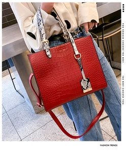 Detail of red crocodile pattern tote bag with snakeskin handles and adjustable shoulder strap