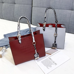 Detail of crocodile pattern tote bag with snakeskin handles on a fashion setting