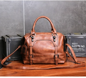 Detail of vintage brown PU leather boston bag with decorative buckle and metal logo plaque