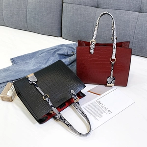 Detailed view of crocodile pattern tote bags in black and dark red with snake print handles
