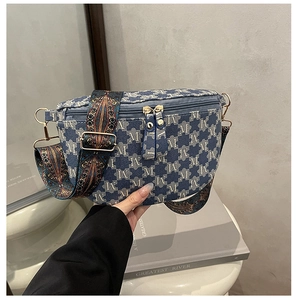 Detail of blue denim fanny pack with golden zippers and vintage jacquard strap