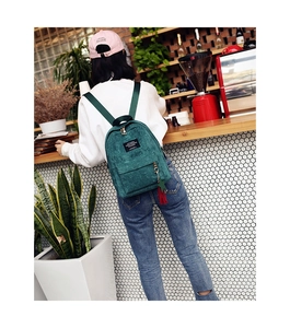 Detail of dark green corduroy backpack with living traveling share woven label