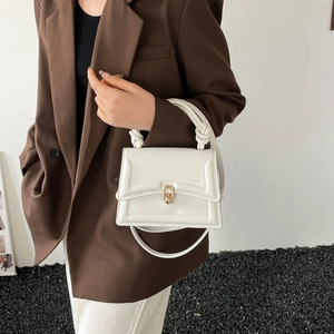 Minimalist white square handbag with braided handle and gold twist lock in street style