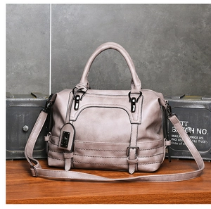 Close-up of taupe Boston bag with textured leather, metallic buckles and brand pendant