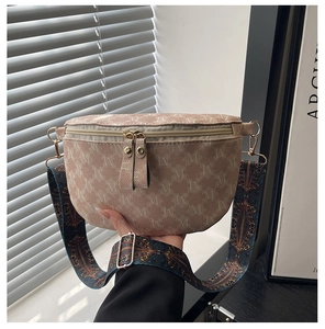 Detail of light beige letter-printed fanny pack with dual gold zippers and ethnic strap