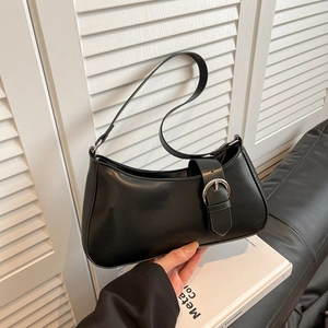 French style black baguette shoulder bag with silver buckle held against modern interior