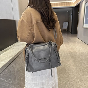 Grey large capacity motorcycle style handbag with tassel detail and adjustable strap