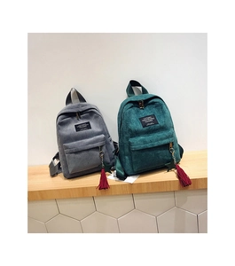 Detail of mini corduroy backpacks in grey and green with tassels and star charms